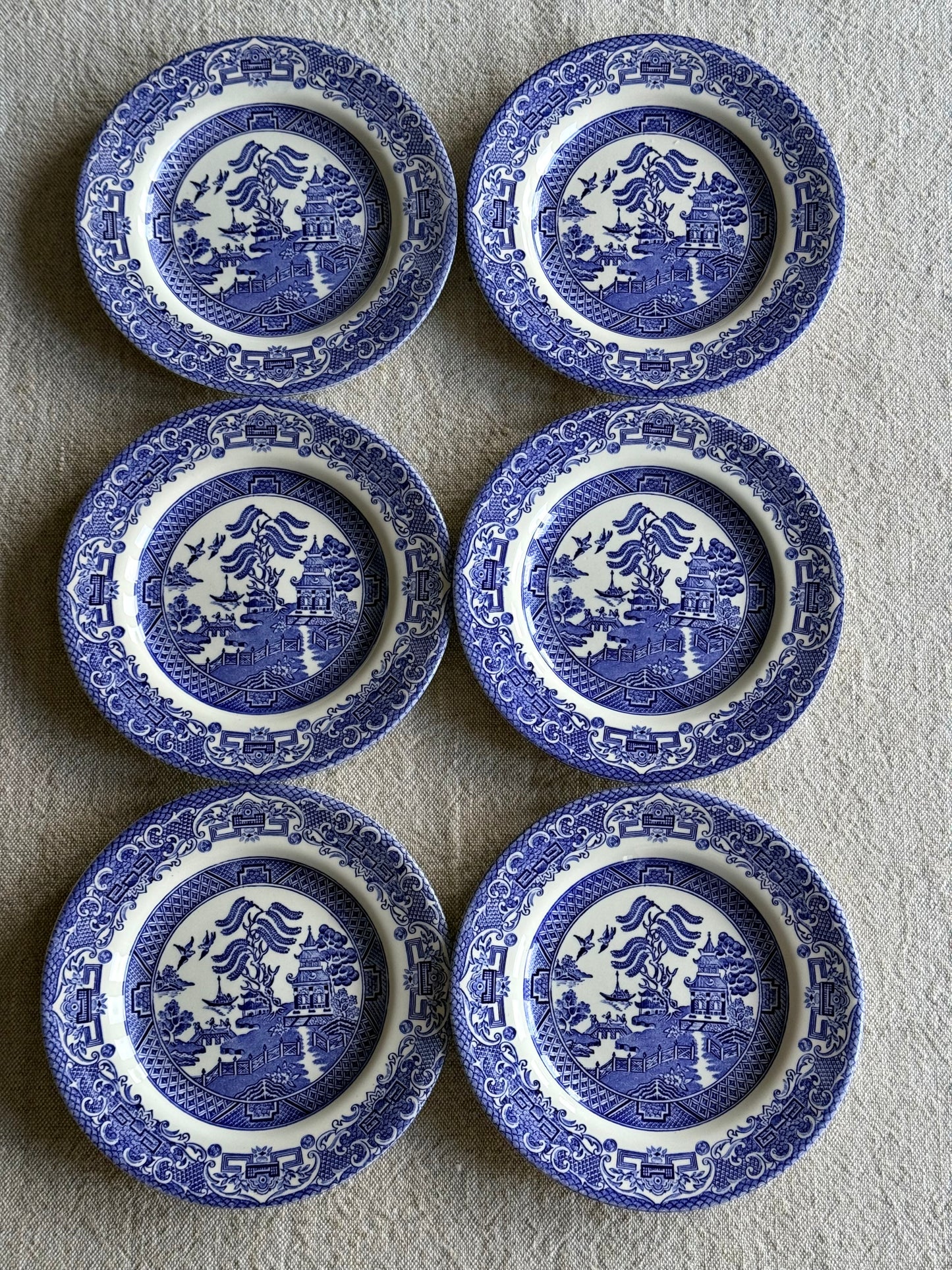 Set of six vintage Blue Willow pattern side plates in classic blue and white.
