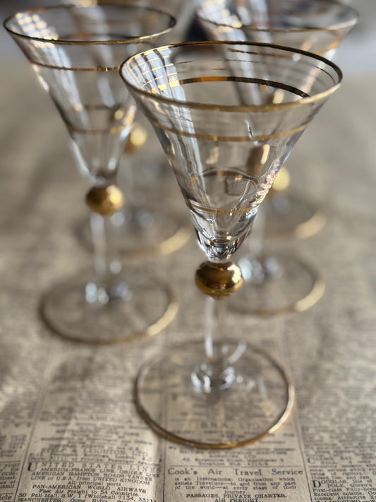 Set of six vintage clear glass stemmed glasses with delicate gold rim detailing and a decorative gold knop on the stem.