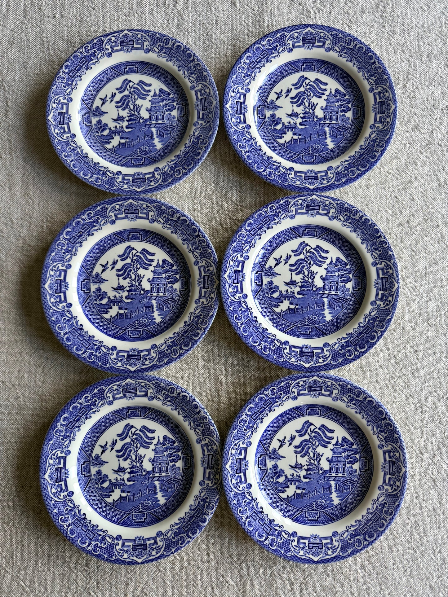 Set of six vintage Blue Willow pattern side plates in classic blue and white.